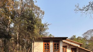 A two-story house with a swimming pool, surrounded by trees and vegetation.