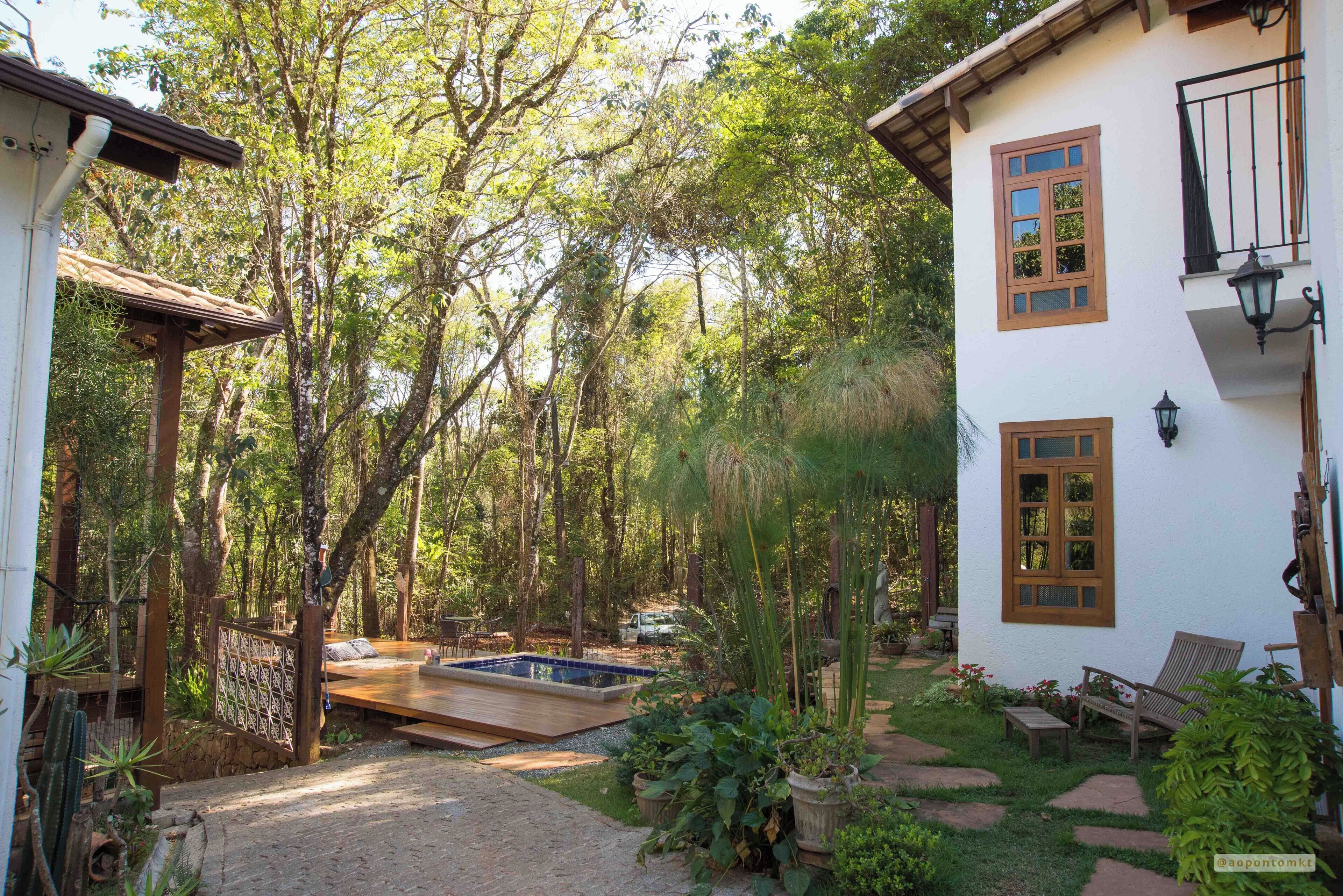 A house with a swimming pool, surrounded by a garden and trees.