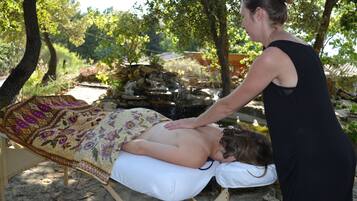 Experience a serene outdoor massage amidst lush surroundings and soothing sounds.