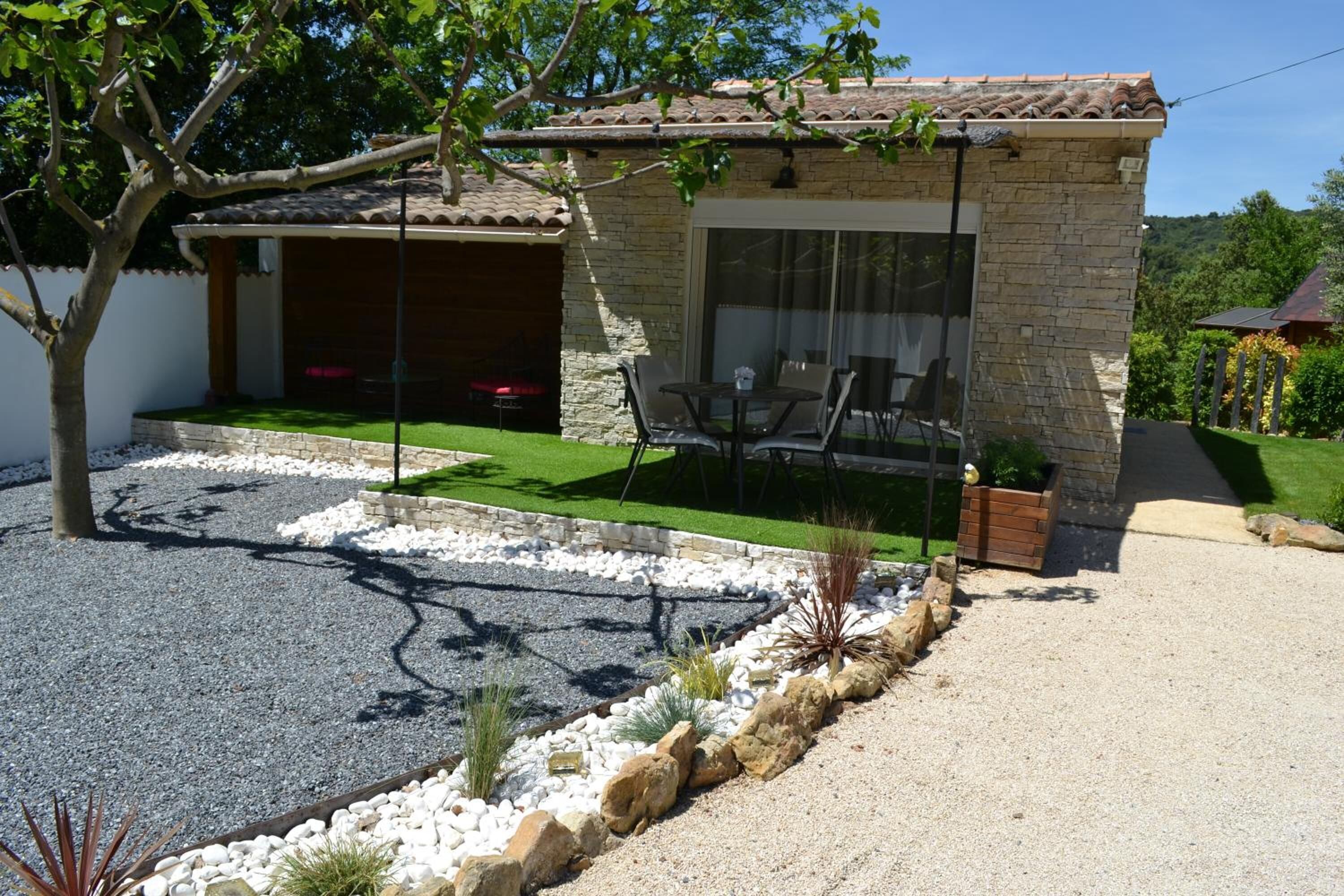 Ein Haus mit Terrasse, Grillplatz und einer Fassade aus Naturstein.