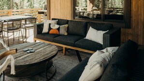 A cozy wooden interior with a sofa and chairs, large windows, and a dining area. - River's Edge 4 Bedroom Home by RedAwning (Breckenridge)