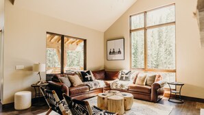 A cozy living room with a brown leather sofa, a patterned armchair, and a wooden coffee table. - River's Edge 4 Bedroom Home by RedAwning (Breckenridge)