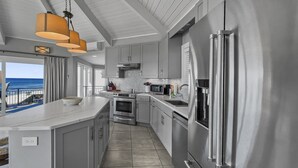A modern kitchen with stainless steel appliances, grey cabinetry, and a large island.
