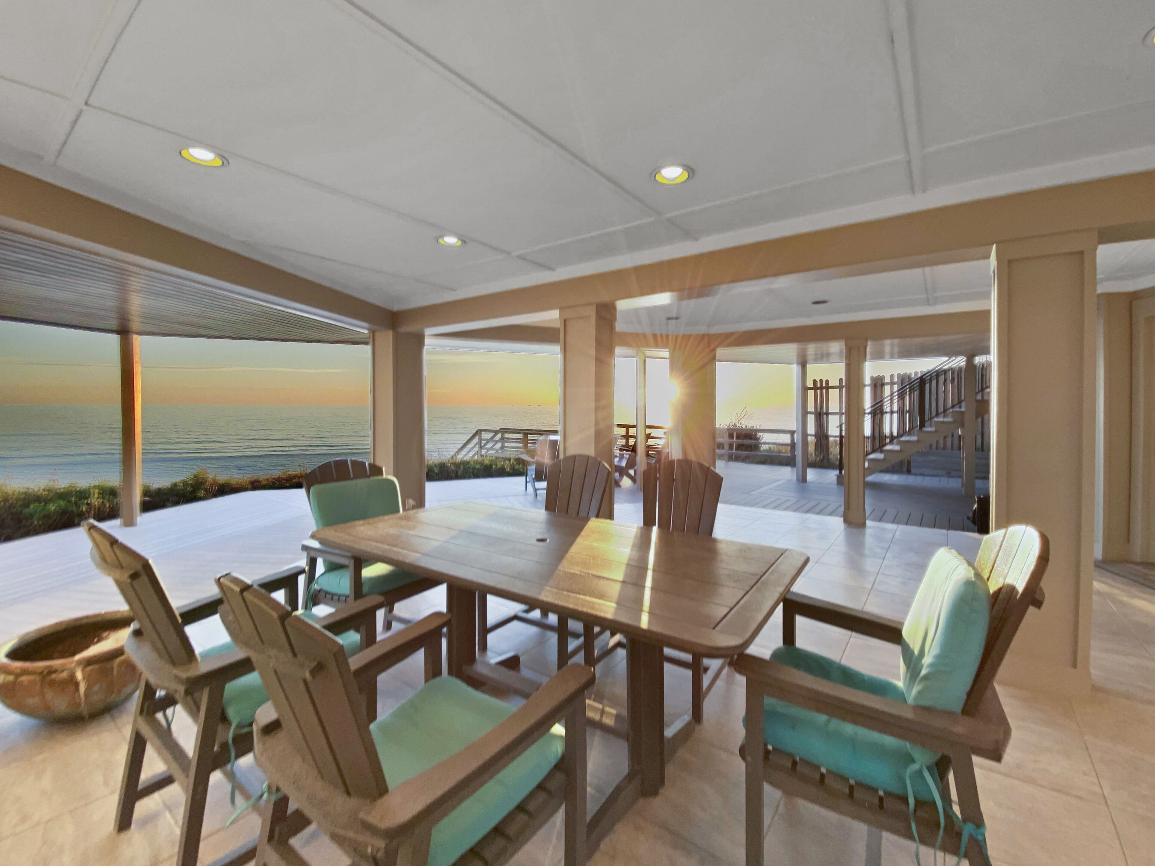 A spacious dining area with a view of the ocean, featuring a large table and several chairs.