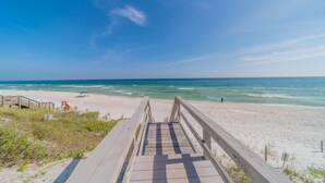 A wooden boardwalk leading to a beach with a clear view of the ocean.