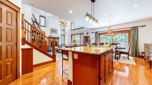 A spacious kitchen with a wooden island, a dining area with a chandelier, and a staircase leading to another level. - Timbers 5 Large Luxury Home with Two Master Suites, Perfect for Families by RedAwning (Mammoth Lakes)