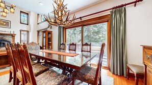 A dining room with a glass-top table, wooden chairs, and a chandelier. - Timbers 5 Large Luxury Home with Two Master Suites, Perfect for Families by RedAwning (Mammoth Lakes)