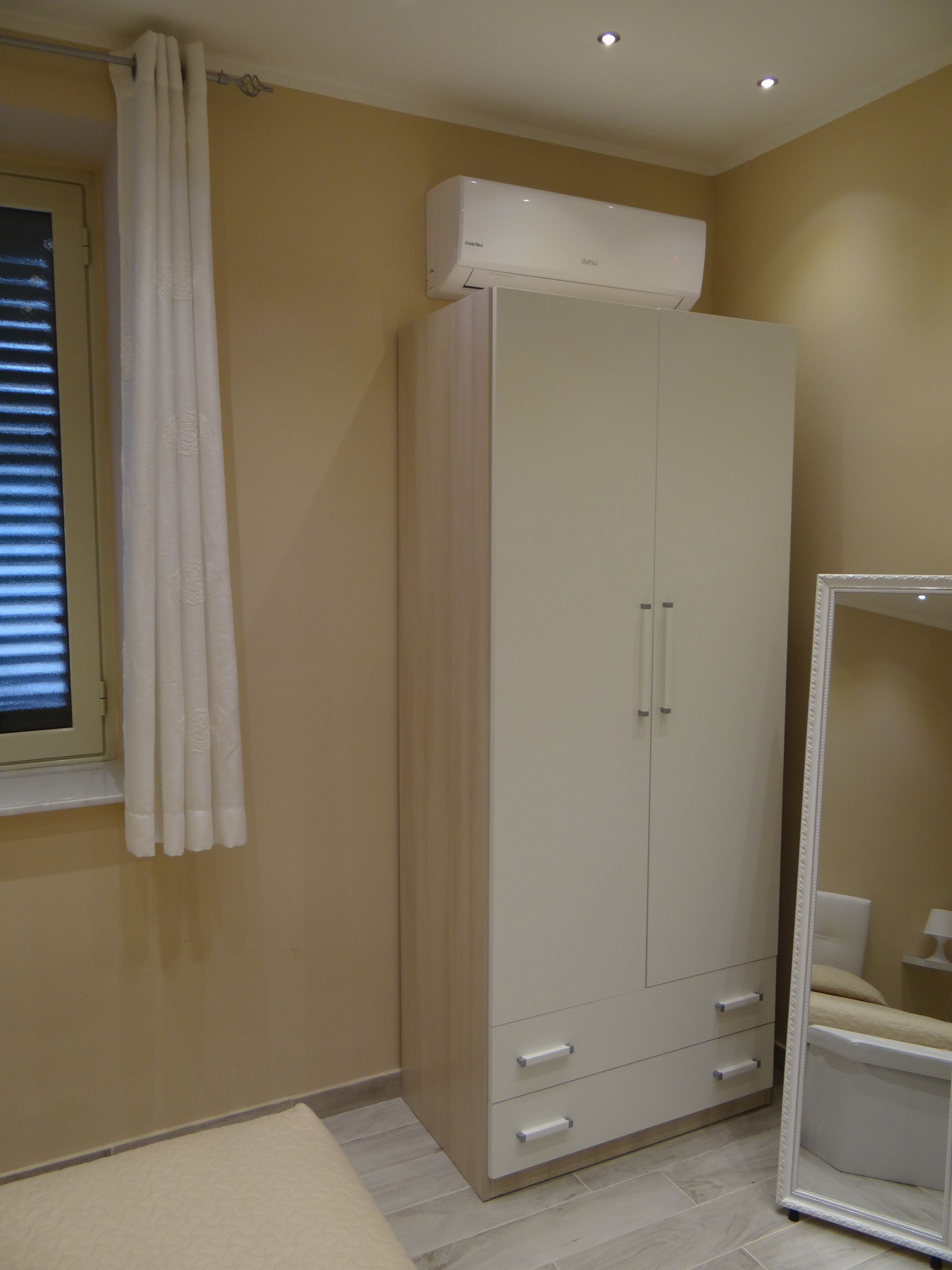 Un dormitorio con un armario, un espejo y una ventana con cortinas.