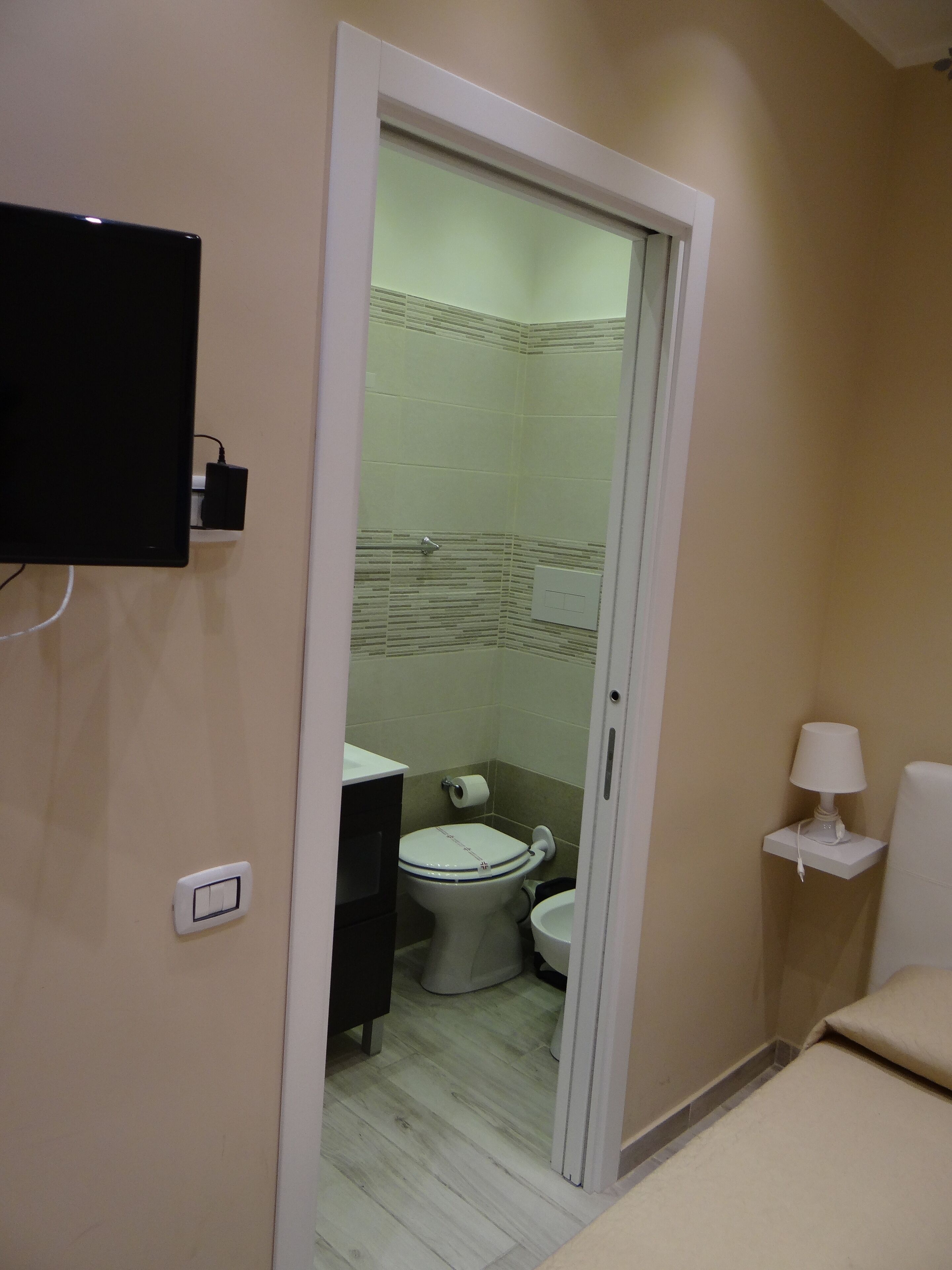 Ein Badezimmer mit Toilette, Waschbecken und einem an der Wand montierten Fernseher.