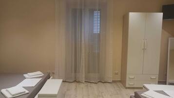 A hotel room with a bed, a desk, a wardrobe, and a shower curtain.