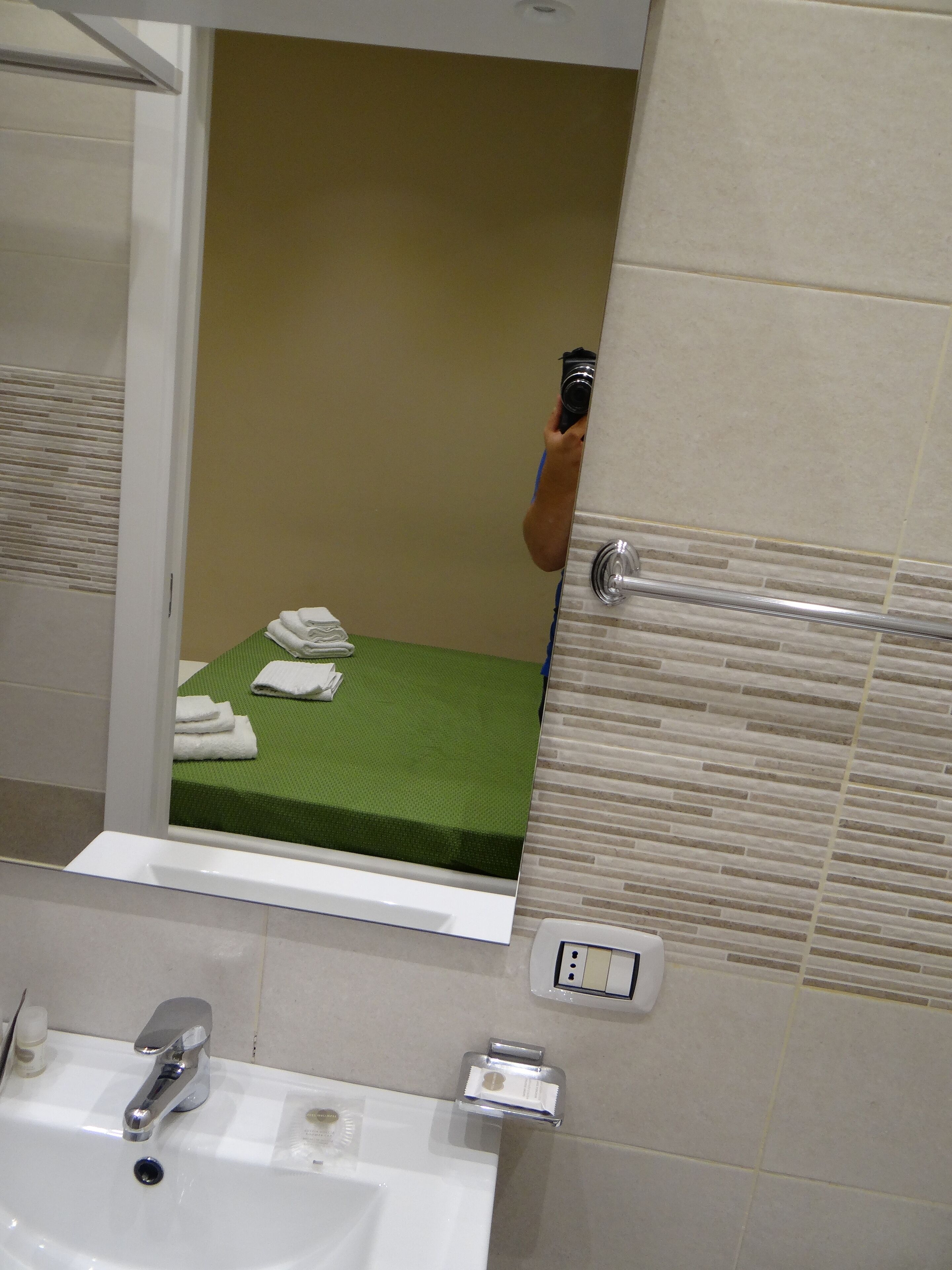 A bathroom with a sink, mirror, and a green mat on the floor.