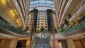 A modern interior with a glass ceiling, a central staircase, and multiple levels. - Liberty Kuşadası - All inclusive (Kusadasi)