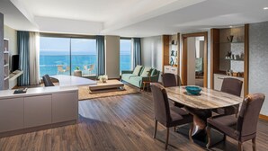 A modern living room with a large dining table, seating, and a view of the sea. - Liberty Kuşadası - All inclusive (Kusadasi)