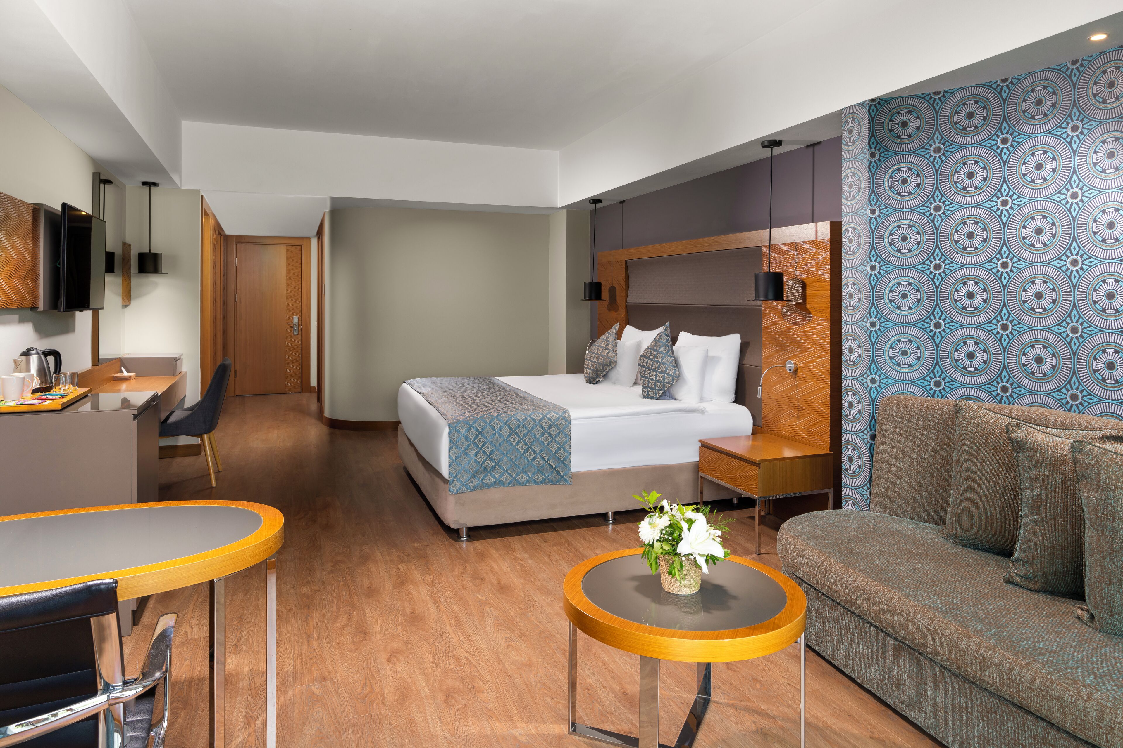 Una habitación de hotel moderna con cama, sofá, zona de comedor y televisor.