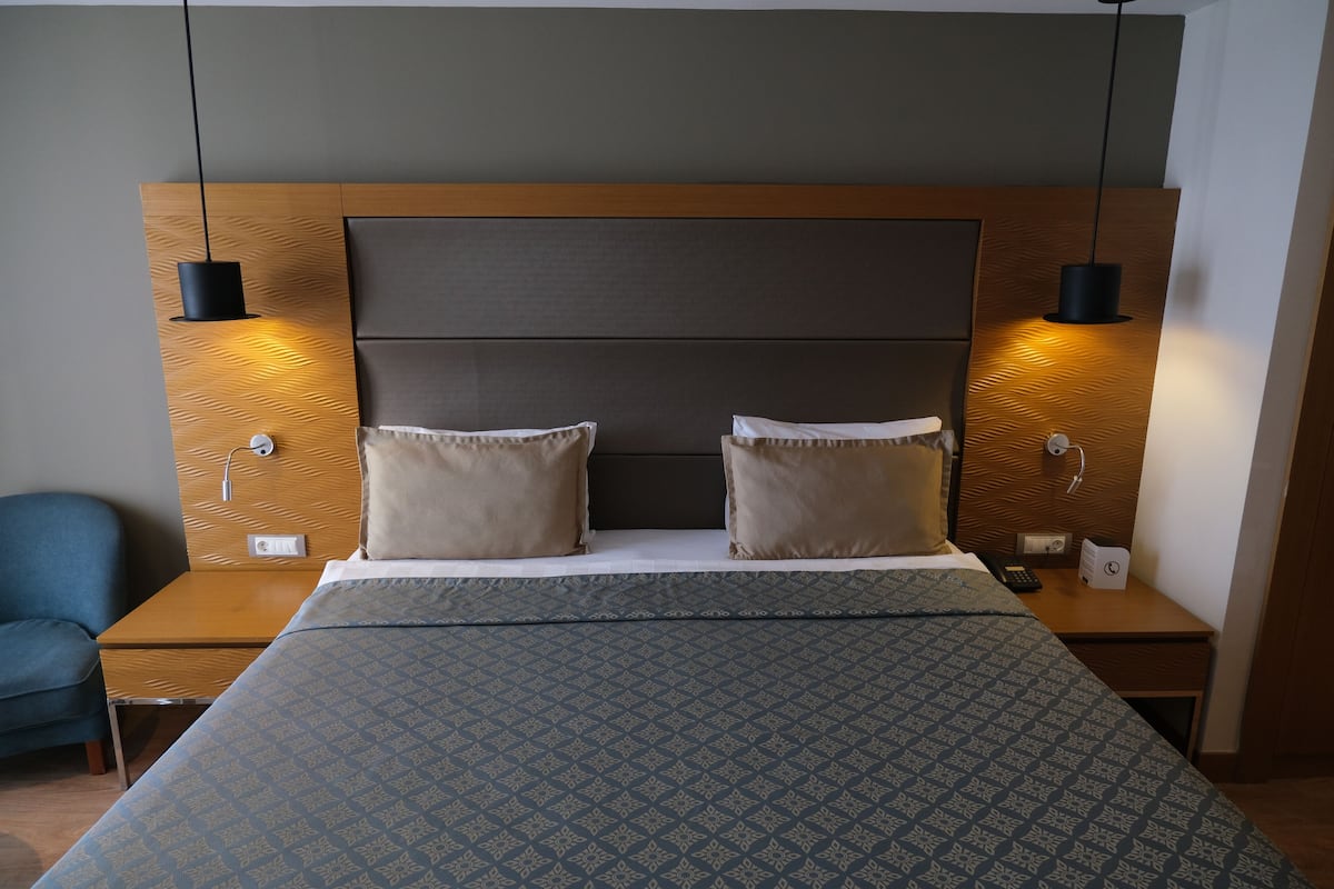 Ein Hotelzimmer mit einem großen Bett, zwei Nachttischen, einem Schreibtisch und einem Stuhl.