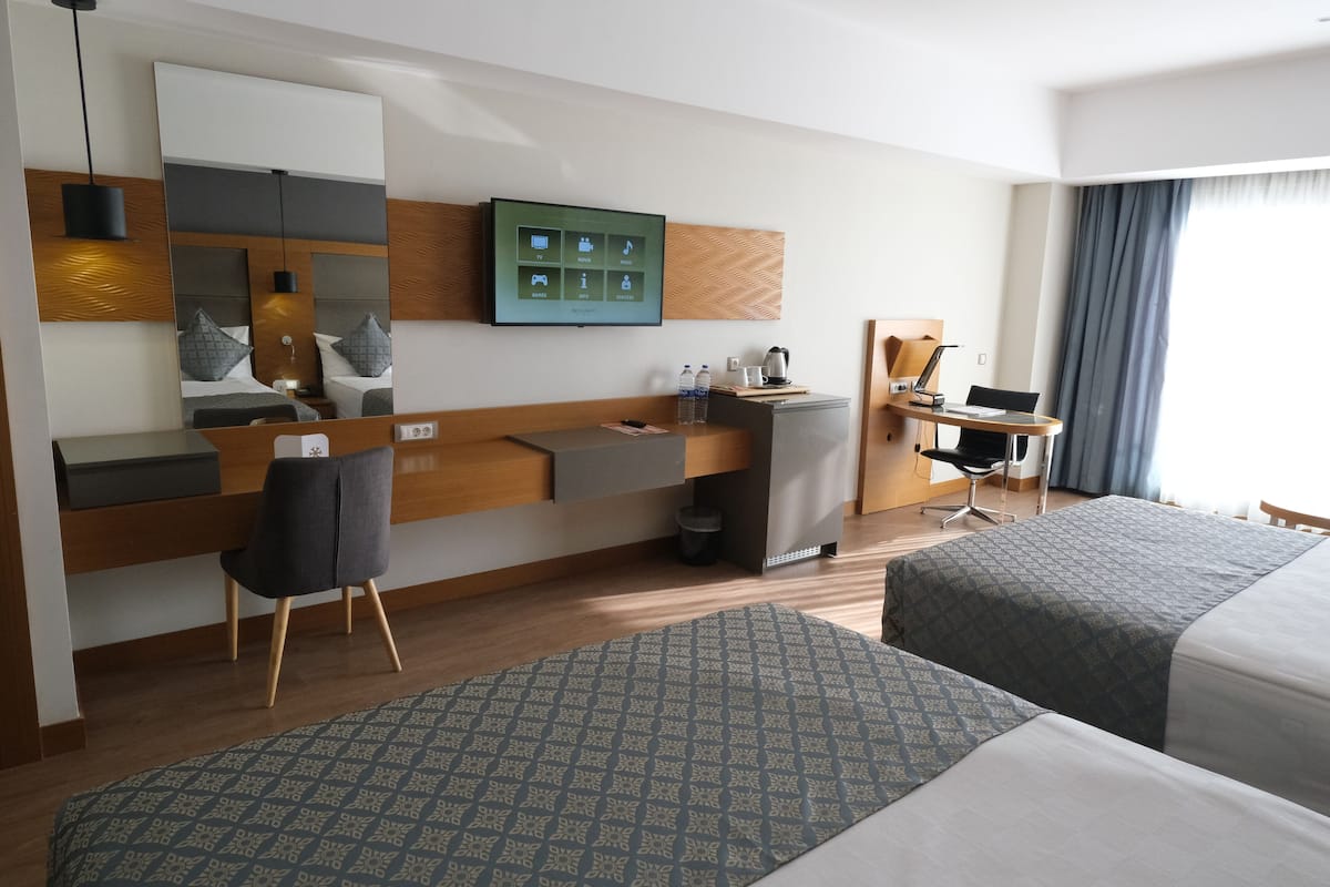Ein Hotelzimmer mit Bett, Schreibtisch, Stuhl, Fernseher und Spiegel.