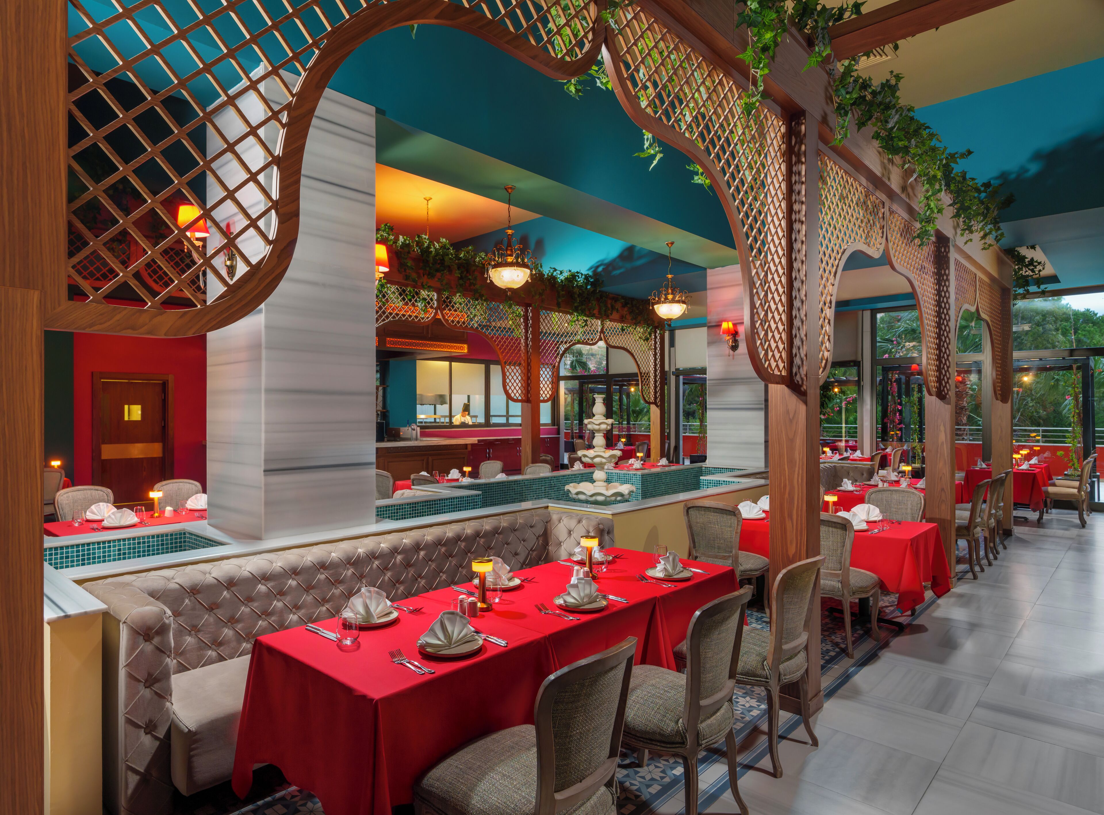 A restaurant with red tablecloths, a central water feature, and a view of the outdoors.