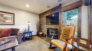 Una sala de estar acogedora con chimenea de piedra, un sillón cómodo, un sofá y una mesita de centro.