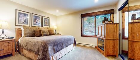 A bedroom with a large bed, wooden nightstands, a wardrobe, and framed pictures on the wall.