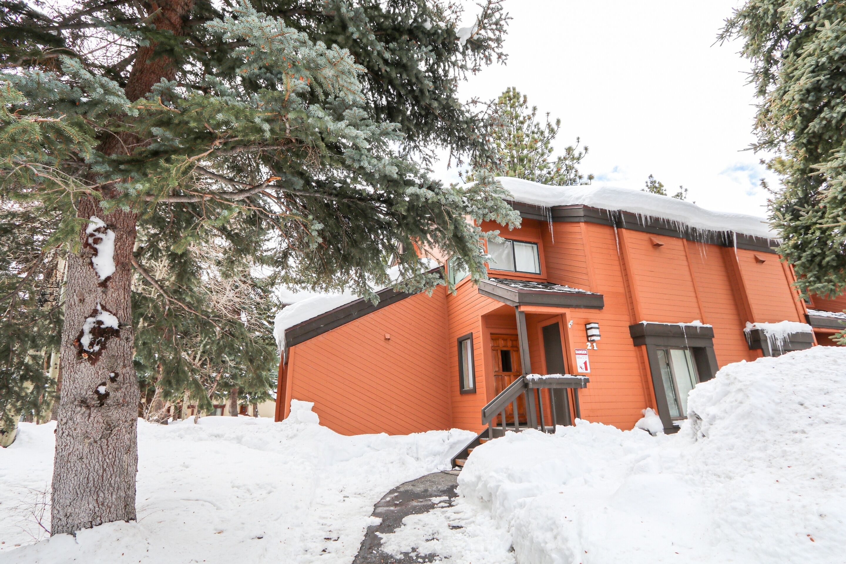 Un edificio de dos pisos con techo cubierto de nieve y una escalera que lleva a la entrada.