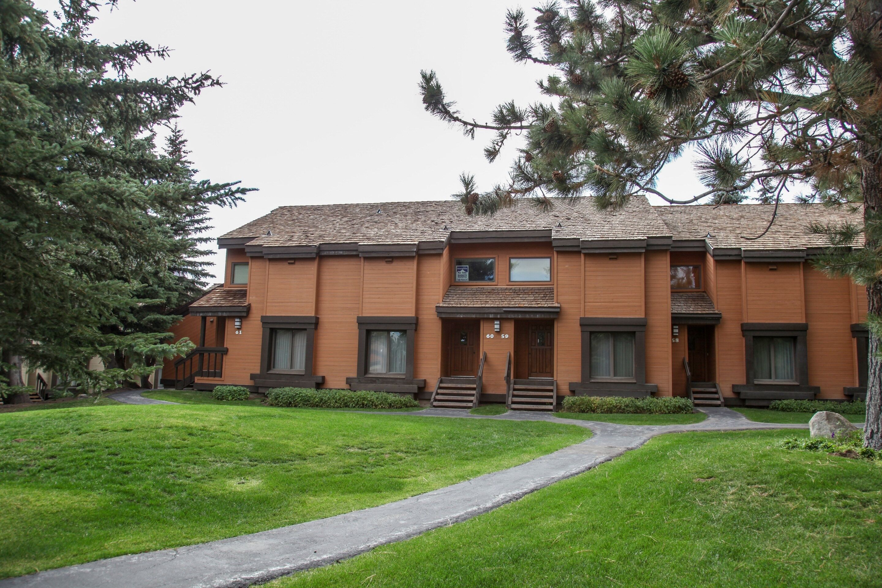 A two-story building with a brick facade, a central entrance with steps, and a small porch area.