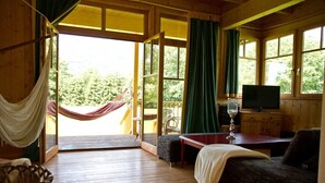 Une cabane en bois avec un hamac, une télévision et un coin repas.