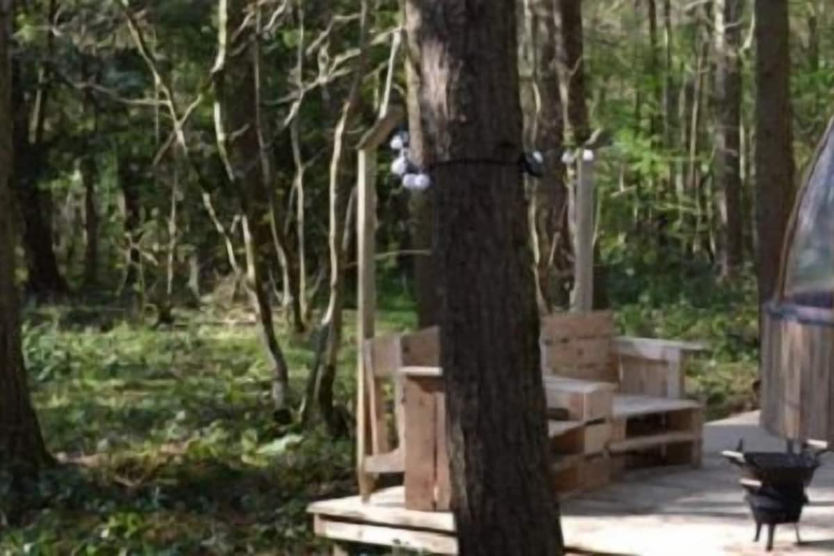 A wooden hot tub structure in a forest.