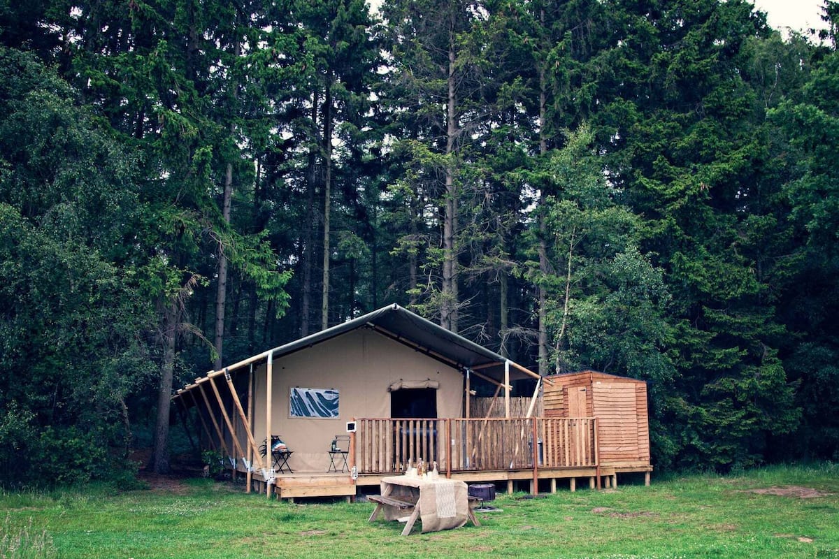 A rustic cabin with a wooden deck, a small porch, and a single window.