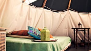 Ein Zeltraum mit Bett, Tisch und Laterne.