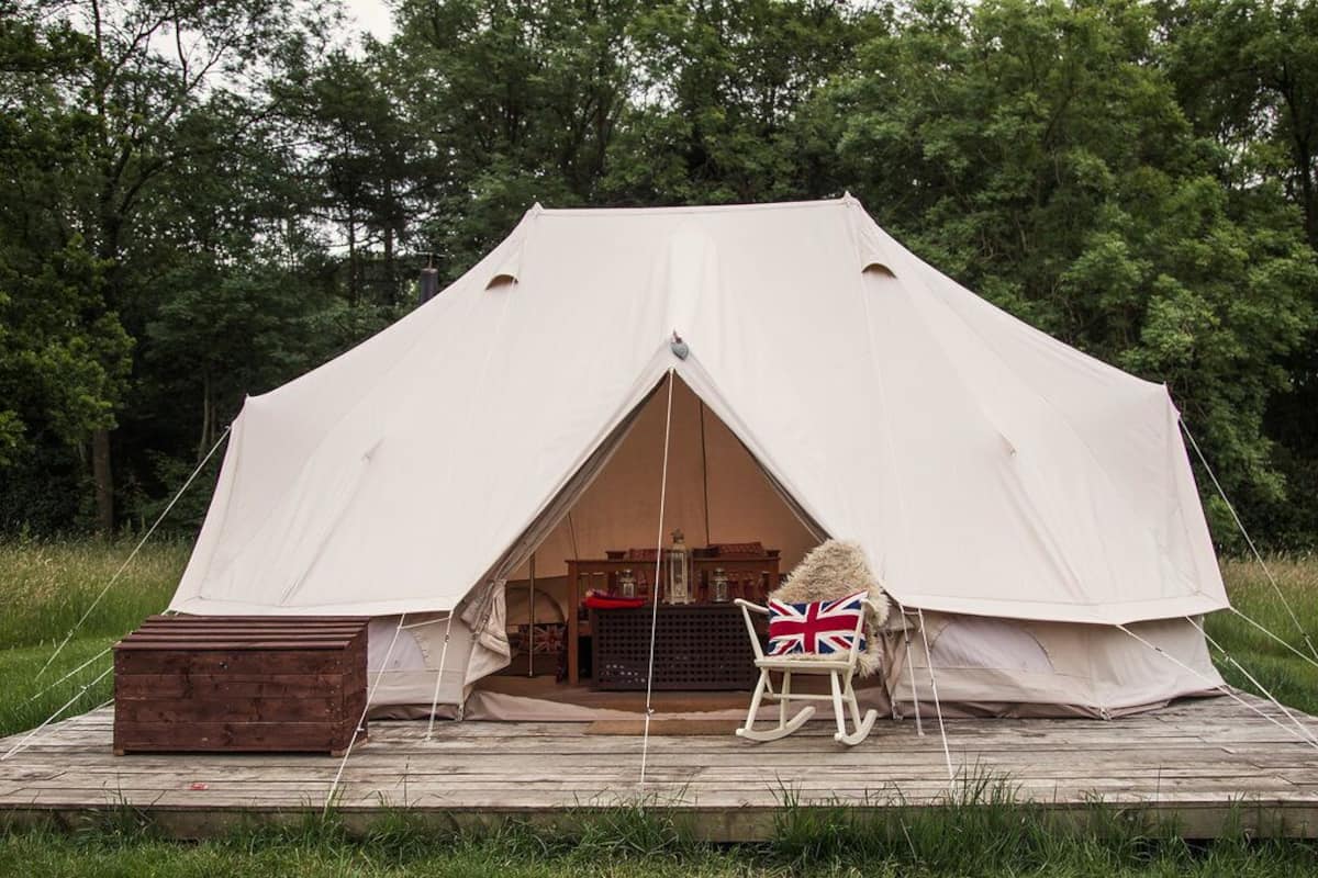 A tent with a wooden deck in front, a rocking chair, and a small wooden box.