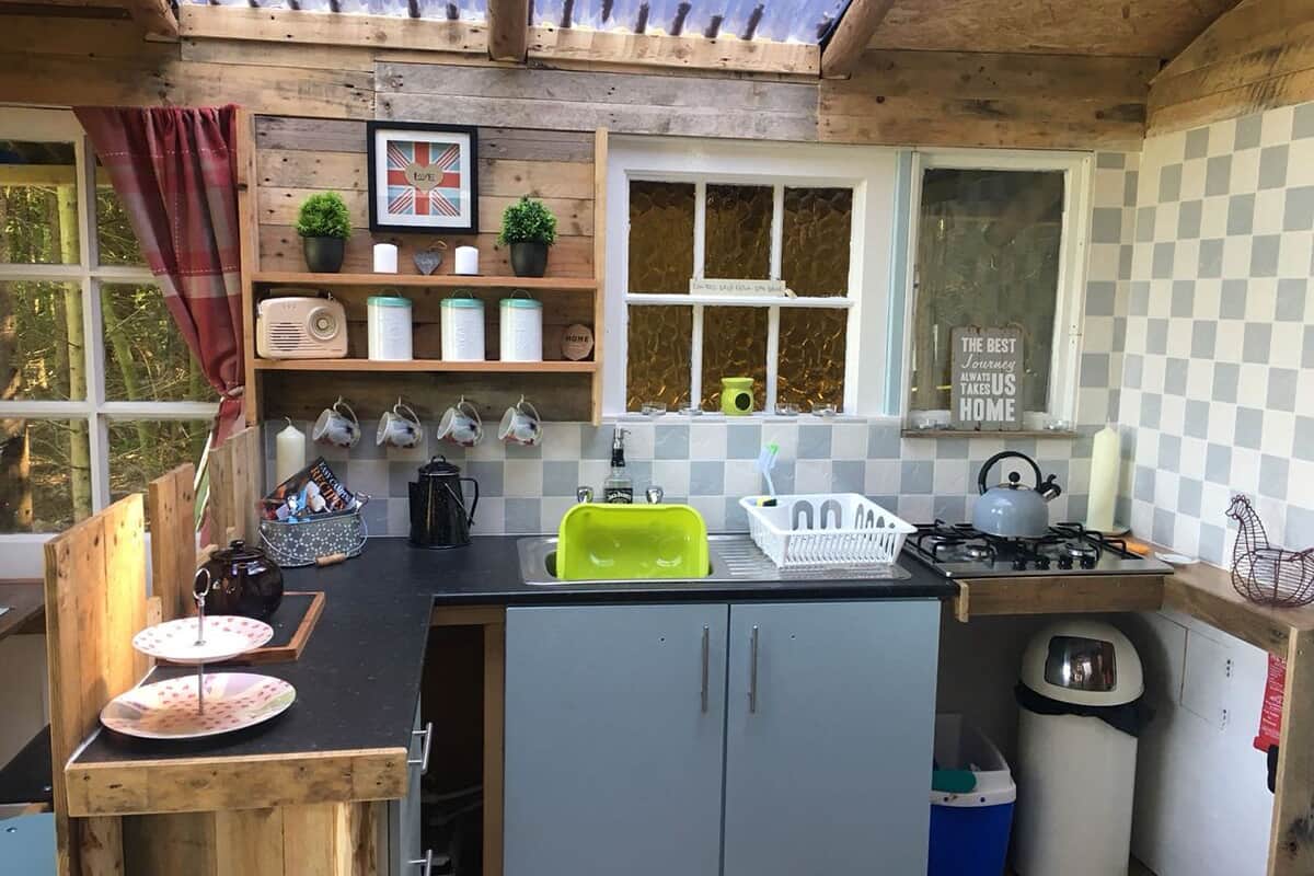 A compact kitchen with a wooden countertop, a sink, a stove, and a window with a view.