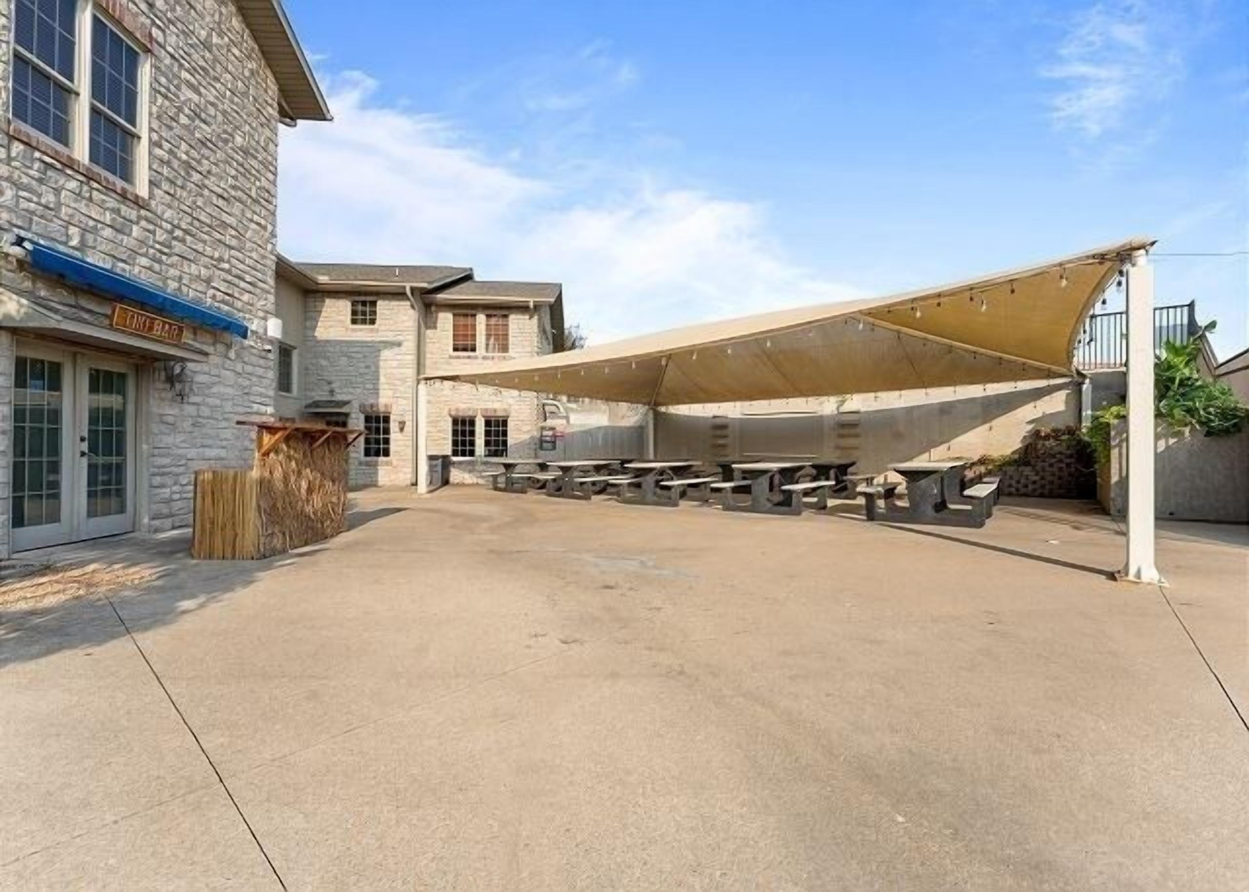 Un espacio al aire libre cubierto con mesas de picnic y un edificio de piedra con un letrero que dice "TIKI BAR".