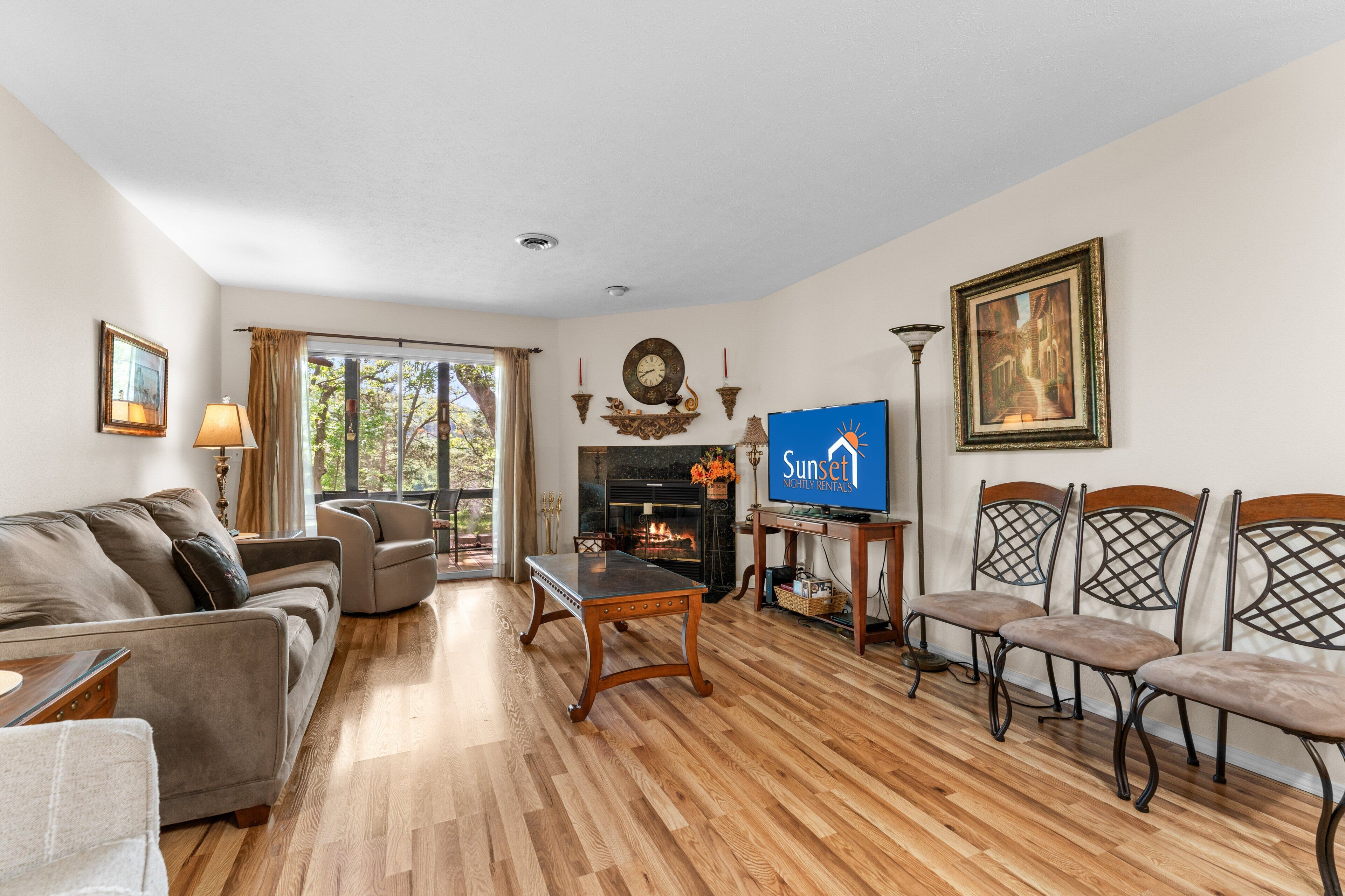 A living room with a sofa, armchair, wooden coffee table, fireplace, television, and framed picture.