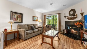 Una sala de estar con chimenea, un sofá, una mesa de centro y un televisor.