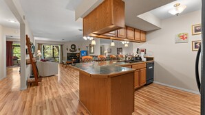 Una cocina amplia con una isla central, armarios de madera e iluminación colgante.