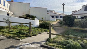 Zona residencial con edificios blancos, un sendero pavimentado y una valla de madera.