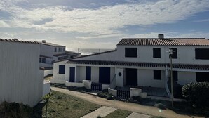 Un edificio costero con techo de tejas, paredes blancas y contraventanas oscuras.