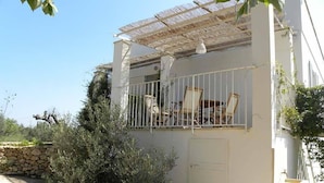 A white building with a covered outdoor seating area, stone wall, and greenery. - Masseria Faresalento (Gallipoli)