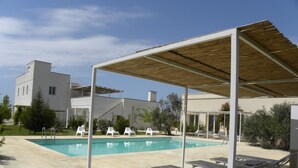 A swimming pool with lounge chairs and a covered area. - Masseria Faresalento (Gallipoli)