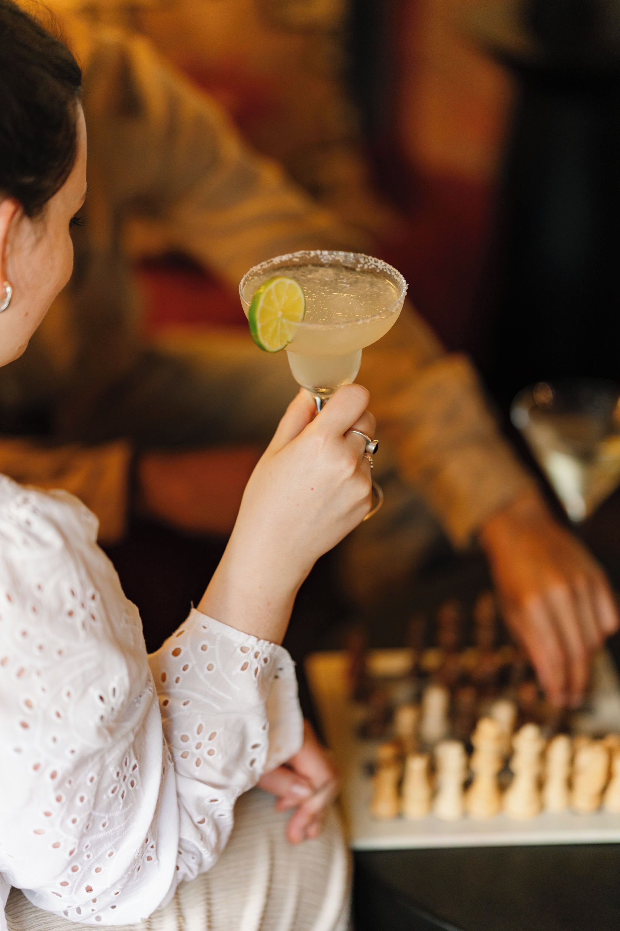 Una persona che tiene un margarita con una guarnizione di lime.