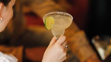 Una persona che tiene un margarita con una guarnizione di lime.