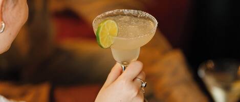 Une personne tenant un verre de margarita garni d’une tranche de citron vert.