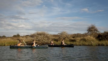 Tres canoas en un río tranquilo con pasajeros.