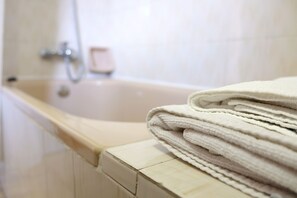 A bathroom with a bathtub, a stack of towels, and a soap dish. - La Terraza de Picos (Cabrales)