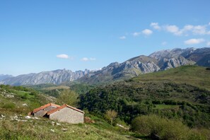 A stone building with a red-tiled roof in a mountainous area. - La Terraza de Picos (Cabrales)