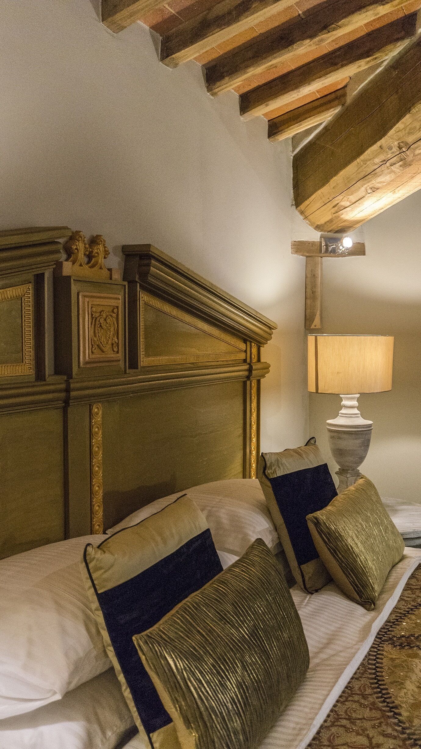 Un dormitorio con cabecera de madera, una lámpara de noche y dos almohadas.