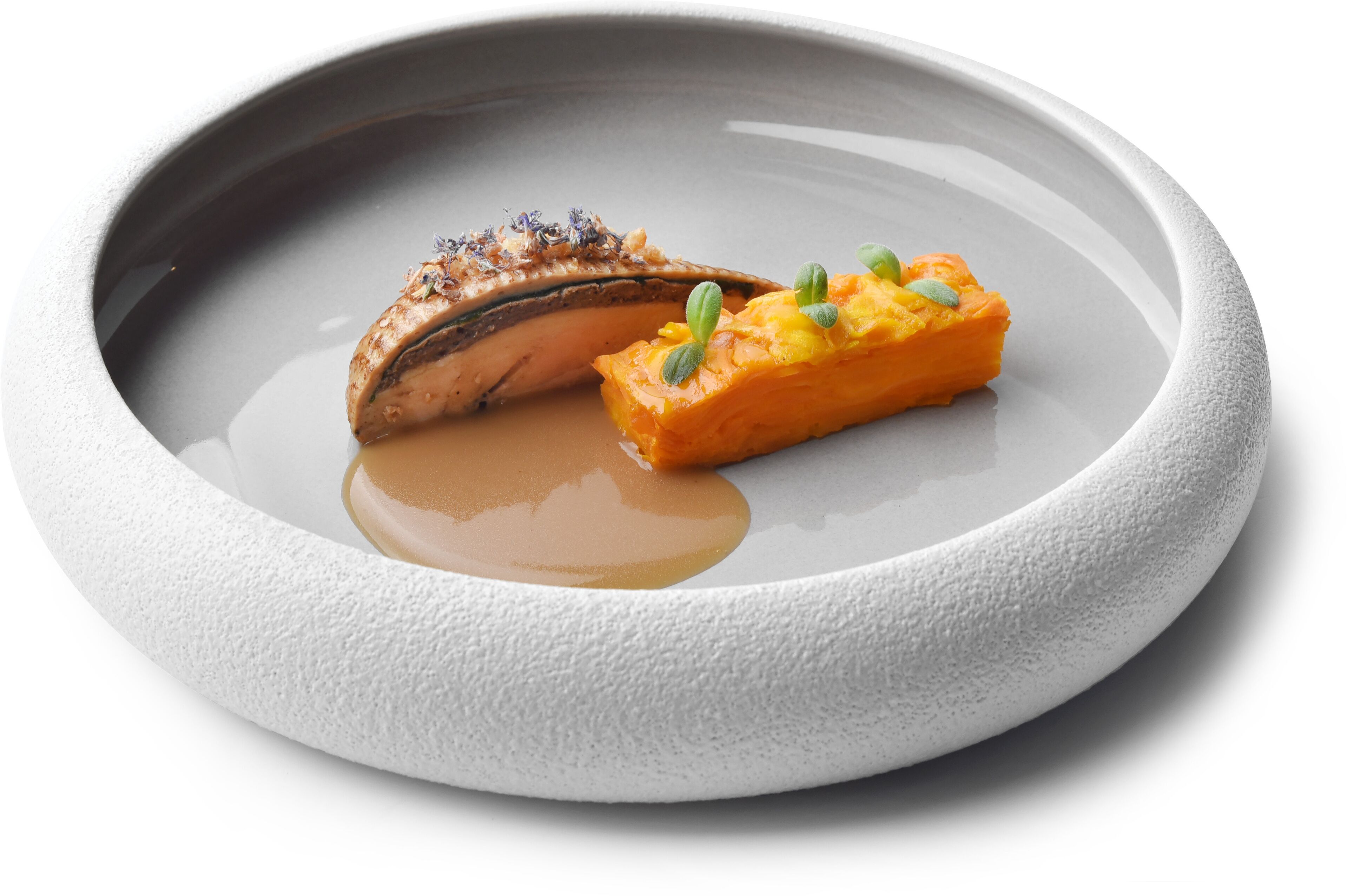Ein weißer Teller mit Lachs und einer Scheibe orangefarbenem Gemüse, möglicherweise Karotte, mit Soße.