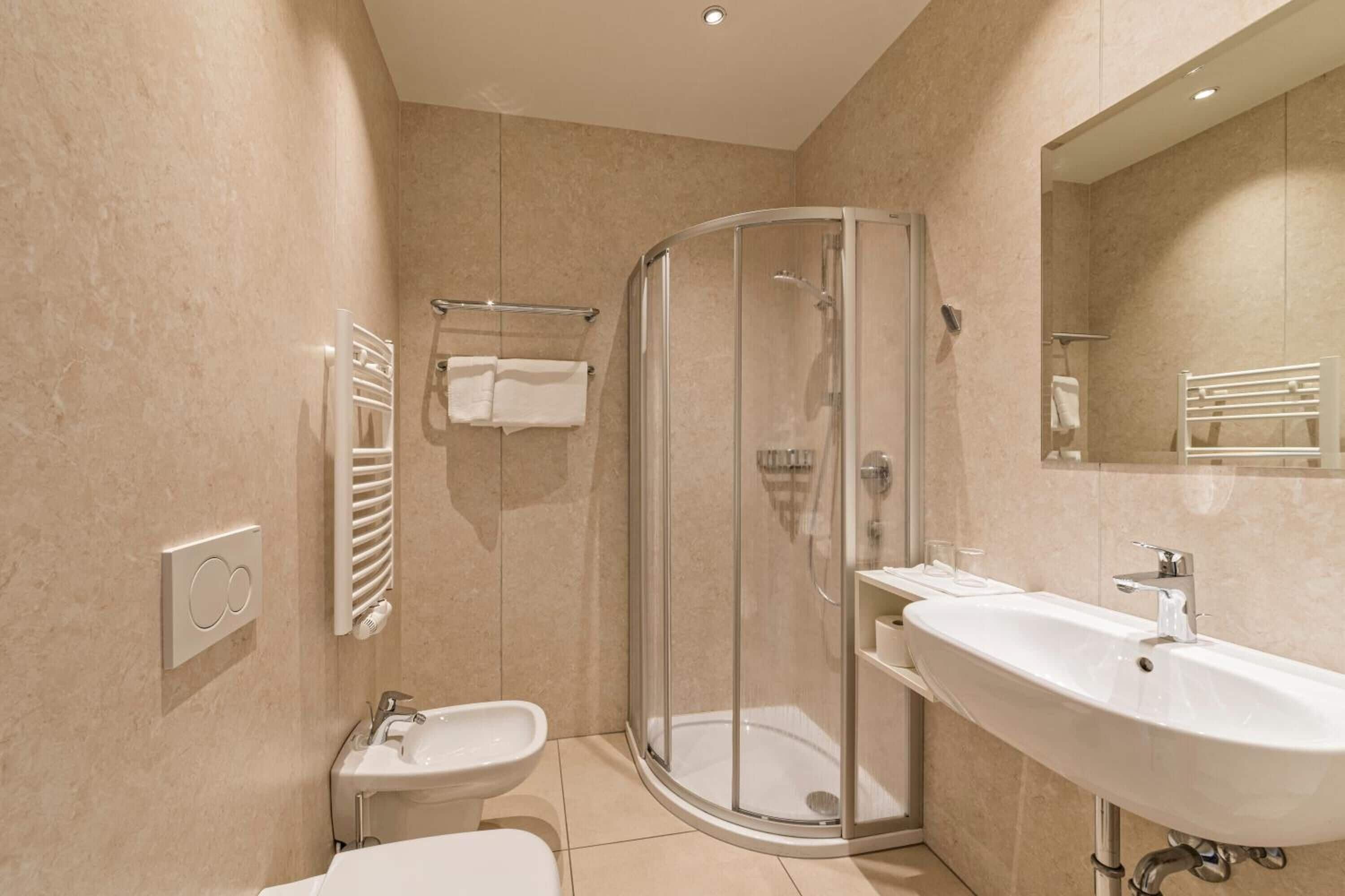 Un baño moderno con ducha de vidrio, lavamanos e inodoro.