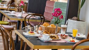Un desayuno con una mesa preparada para dos personas, que incluye croissants, un bol de fruta, una taza de café y un vaso de jugo de naranja.