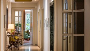 Un pasillo con comedor, un sillón verde y vistas al exterior.